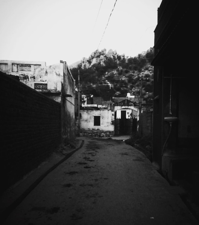 Empty lane in a small Rajasthani town with rocky hills in the background
